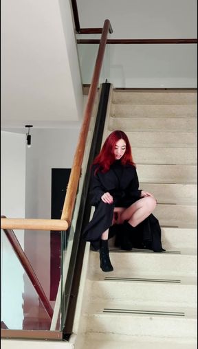 Woman in black coat sitting on staircase