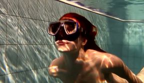 Hot redhead babe in the diver mask swimming under water