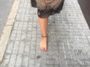 young female hippie is walking barefoot in public street