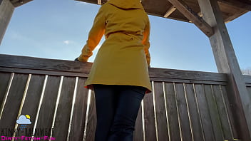 hot girl in yellow rubber raincoat, pants and boots taking a sexy walk in public