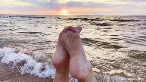 Beautiful Wrinkled Soles and Toes Wiggling Against the Backdrop of a Sunset on the Sea Beach