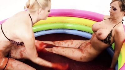 Cheerful babes play with jello in the pool and finger each other