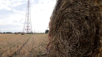 Naked girl playing with a bale of straw