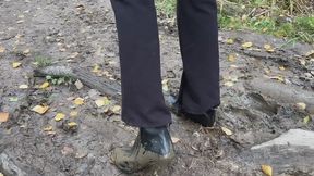 Girl in ankle boots, she wants to walk along the path and climb the hill, but her high-heeled half-boots slide down the muddy slide (reissue)
