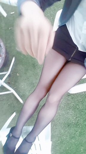 Young asian girl in mature outfit and black pantyhose walks through apartment garden