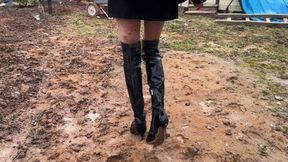 A girl in boots walks through very deep mud, gets stuck in it up to her knees, it's hard for her to get out ?re-realize)