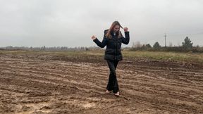 A girl in high-heeled shoes climbed into a mud field and began to walk there