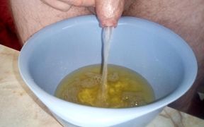 Close up when John is peeing into a plastic bowl