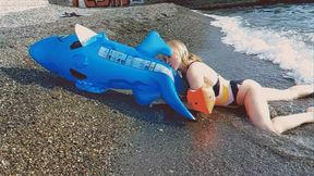 Alla inflates a blue inflatable shark with her mouth on the beach!!!