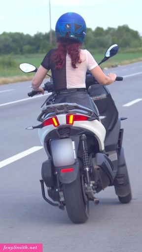 Jeny Smith rides a motorcycle in a short skirt.
