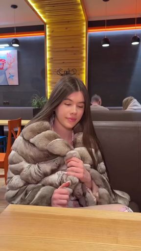 Blonde woman in fur coat sitting at restaurant table