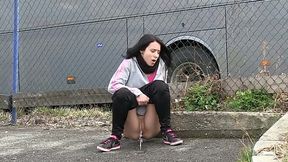 Straight haired emo chick pulls down black jeans to pee at the bus parking