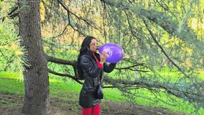 Blowing to pop a purple balloon with a long neck outdoors
