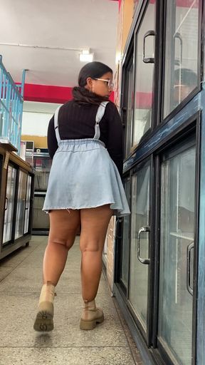 Woman in denim skirt walking past store