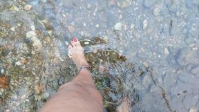 Walking barefoot through a river with many stones (1)