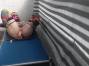 Caged sissy plays with her dildo on public balcony