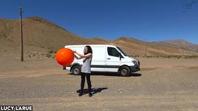 vanlifer pops a giant orange balloon in the desert