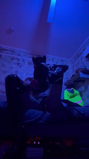 Putting leather boots on in a leather mask
