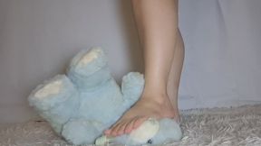 Squashing the little blue bear with her feet