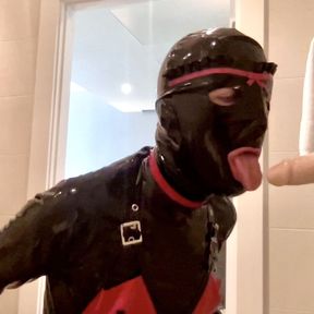 Latex Alice blows and deep throats a dildo while on her knees in the bathroom