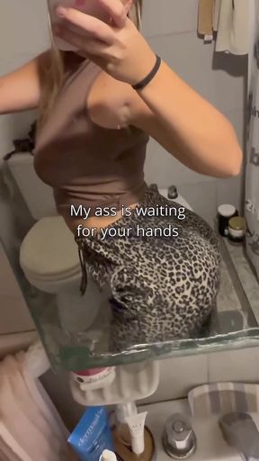 Woman in leopard print pants taking selfie in bathroom mirror