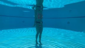 Wrist self-bondage in the resort pool in a rainbow bikini