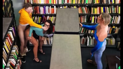 Mandy Waters - Brunette with glasses gives a cap to a student in the library