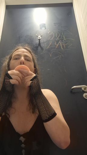 Alana playing with a dildo in a public toilet stall.