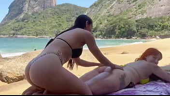 Ruiva e morena ficam com tes&atilde_o na praia e se pegam escondidas atr&aacute_s da uma pedra