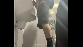2 boys in sneakers having fun at public toilets&#039_ urinal