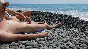 The big cock is getting jacked off by a busty stranger on a rocky beach