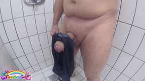 In a public shower, I masturbate my wet cock, finger my hole, and squirt my cum onto a black swimming trunk.