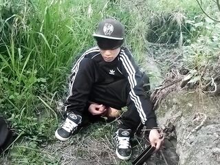 Cute Oriental homosexual twink in a ebony-and-white adidas tracksuit and Campus sneakers masturbates and cums outdoors