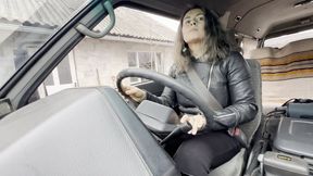 Driving car in leather jacket and patent leather boots