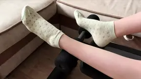 Fitness girl in green socks doing leg exercises on a sports bench