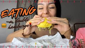 Eating a double hamburger.