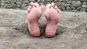 Mature woman buried on the beach with her feet sticking out (1)
