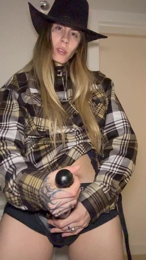 Woman in plaid shirt and cowboy hat holding a ball