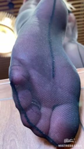 Goddess with long legs and big ass in black pantyhose on the table plays with a toe ring above you