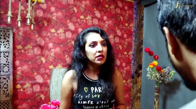 Dark-haired couple explores passion in a floral-walled bedroom