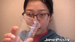Sweet Japanese girl uses cup to pee while sitting on the toilet