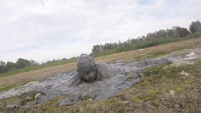 Amateur fellow is covering himself in mud out in the open