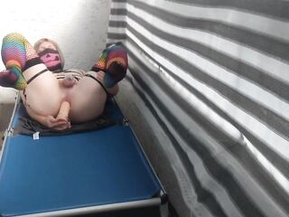 Caged sissy plays with her vibrator on public balcony