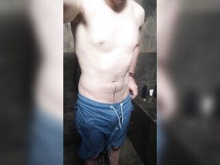 Je me masturbe sous la douche en short de bain et fait grossir ma grosse bite toute mouillée.