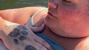 Nude lady with large globes floats on the river