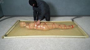 Mummification with bandages and rope bondage with ankle brace in a vacuum bed
