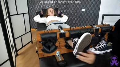 Bound brunette undergoes intense foot tickling session on restraint bench