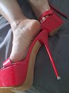 Red very high heels mules dangle in bed