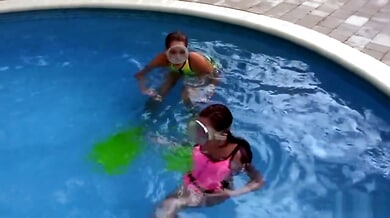 Two women share intimate underwater kisses in a backyard pool wearing snorkel masks