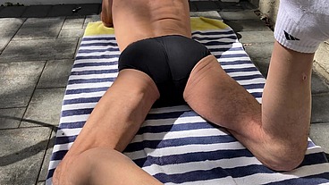 Laying in the sun on striped towel and stretching away the pain in dark tight briefs